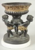 A GOOD BRONZE CIRCULAR COMPORT, the bowl held by three cupids on a circular base. 12ins high, 8.5ins