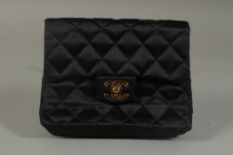 A SMALL CHANEL PADDED BLACK EVENING BAG 6.5ins long with entwined gilt metal and leather chain,