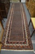 A PERSIAN RUNNER OR HALL CARPET, decorated with stylised Boteh design 450cm x 110cm.
