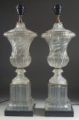 A GOOD PAIR OF GLASS TWIST URN SHAPED PEDESTAL LAMPS on a marble base. 23ins high.