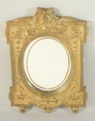 A GOOD GILDED BRONZE MIRROR with oval mirror, the case with bust and swags.