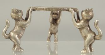 A CHINESE WHITE METAL COIN HELD ALOFT BY THREE CATS