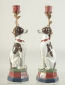 A PAIR OF BLACK AND WHITE PORCELAIN SEATED DOG CANDLESTICKS with metal candle holders. 13ins high.