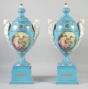 A LARGE PAIR OF CONTINENTAL LIGHT BLUE TWO HANDLED URNS AND COVERS with classical female heads, on