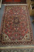 A PERSIAN RUG, pink ground with floral decoration 168cm x 103cm