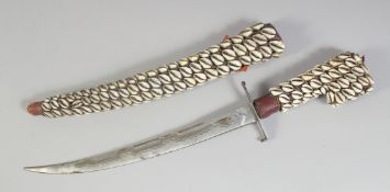 A COWRIE SHELL COVERED DAGGER AND SHEATH. 18ins long.