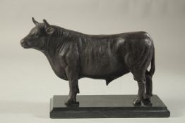 A BRONZE STANDING BULL 9ins long, on a marble base.