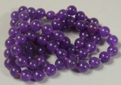 A STRING OF EIGHTY BLUE JADE BEADS 26ins long.