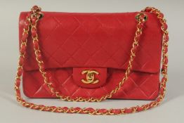 A CHANEL PADDED LEATHER RED HANDBAG, with entwined leather and gilt straps. 9ins wide.