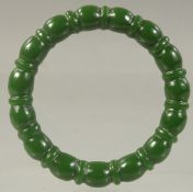 A CHINESE CARVED GREEN JADE BANGLE. 2.75ins
