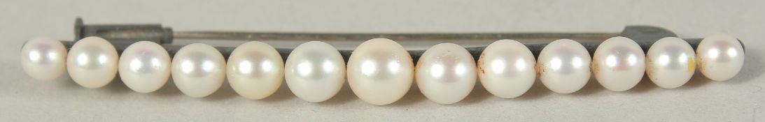A BAR BROOCH set with 12 graduated cultured pearls.