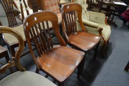 A pair of Edwardian mahogany chairs with vertical slat backs, solid seats on tapering legs.