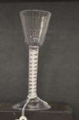 An 18th century English wine glass with inverted bowl and air twist stem.