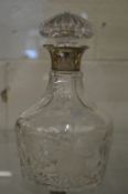 A cut glass decanter with silver collar.