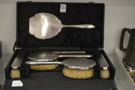 A cased silver backed six piece dressing table set.