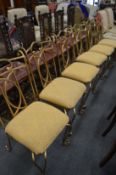 A set of six gold painted wrought iron dining chairs with upholstered seats.