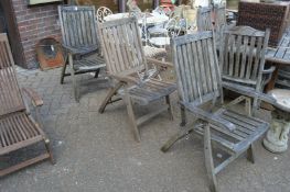 Three weathered teak folding garden armchairs.
