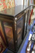 A Victorian ebonised two door display cabinet with ormolu and porcelain mounts.