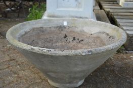 A large circular reconstituted stone garden planter.