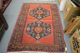 A Persian design rug, red ground with two large central medallions, 158cm x 128cm.