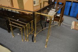 A brass and smoked glass console table with a set of three matching occasional tables.