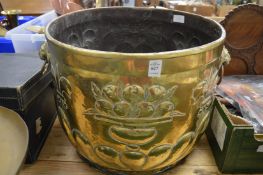 A large embossed brass coal or log basket with lion mask handles.