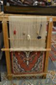 A carpet making loom with sample carpet.