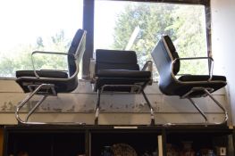 A set of three stylish chrome and leather armchairs.