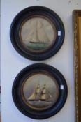 A pair of colour oiliographic prints depicting sailing ships in circular ebonised frames.