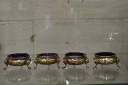 A set of four silver circular salts with blue glass liners.