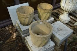 A set of three reconstituted stone circular planters.