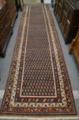 A Persian runner or hall carpet, decorated with stylised Boteh design, 450cm x 110cm.