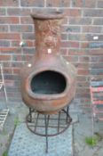 A chiminea with wrought iron stand.