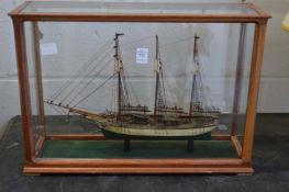 A good small model of a three masted sailing ship in a glass display case.