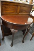 A mahogany demi-lune fold over card table with carved cabriole legs.