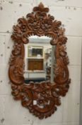An Eastern carved wood wall mirror.