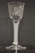 An 18th century English wine glass with inverted bowl and air twist stem.