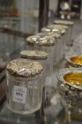 Seven various cut glass dressing table jars with silver lids.