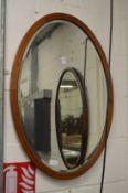 An inlaid mahogany oval wall mirror.