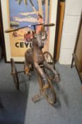 A carved wood and wrought iron hobby horse style tricycle.