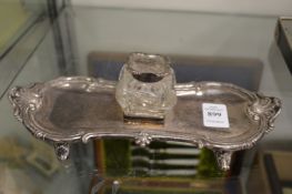 A silver desk stand with inkwell.