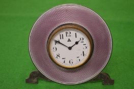 A silver circular bedside clock with enamel decoration.