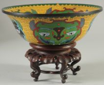 AN UNUSUAL CHINESE YELLOW GROUND CLOISONNE BOWL, on hardwood stand, bowl 23cm diameter.