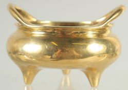 A SMALL CHINESE GILT BRONZE TWIN HANDLE TRIPOD CENSER, the base with character mark, 9cm wide.