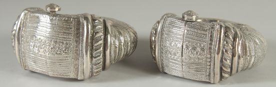 A PAIR OF ISLAMIC SILVER SLAVE BANGLES, with embossed and chased decoration, weight 590g.