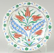 AN OTTOMAN TURKISH IZNIK GLAZED POTTERY PLATE, with tricolour foliate decoration, 31cm diameter.