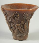 A GOOD CHINESE HORN LIBATION CUP carved with figures and foliage. 5.5ins high.