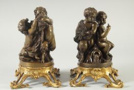 A GOOD PAIR OF BRONZE AND ORMOLU CUPID GROUPS each with two cupids, on ormolu bases. 9.5ins high.