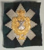A SILVER AND GILT BLACK WATCH BADGE 