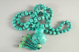 A LONG TURQUOISE BEAD NECKLACE AND PENDANT.